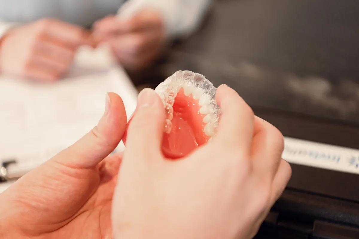 Clear retainer held over a dental model