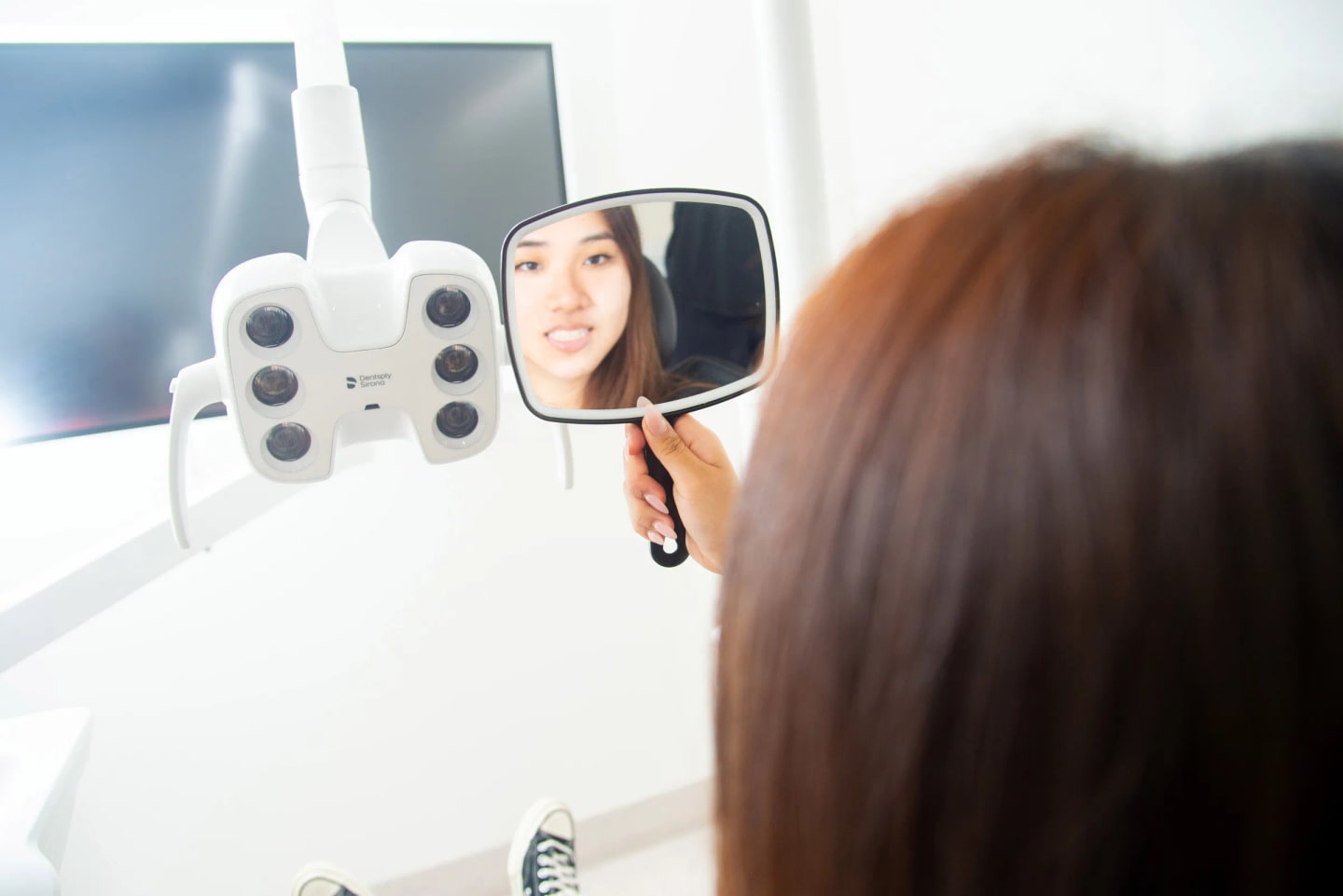 Patient viewing her teeth in a mirror during a dental appointment at Ivy Dental